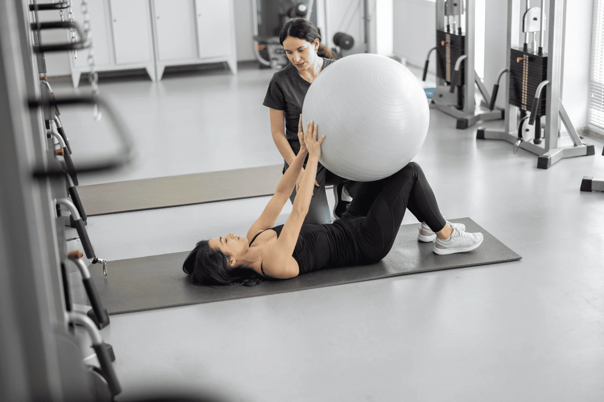 Physiotherapeut-Wittenberg-Rückenbehandlung Frau trainiert mit Gymnastikball, während ein Physiotherapeut in Wittenberg assistiert.